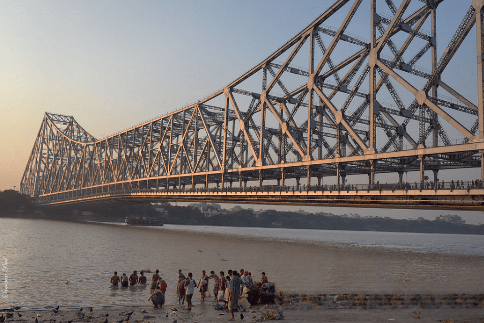 Howrah Bridge in Kolkata, West Bengal, India, illuminated at night, spanning the Hooghly River with its distinctive steel structure.